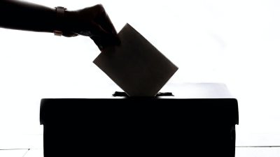 Någon lägger ner en röstsedel i en valurna.